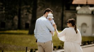 a man holding a baby while standing next to a woman