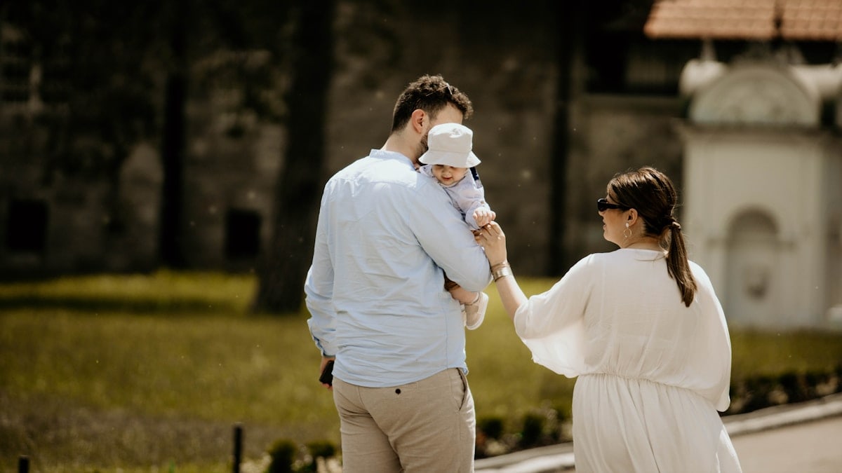 a man holding a baby while standing next to a woman